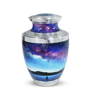 Celestial Journey 10-inch Treisty shape aluminum cremation urn featuring a High-Gloss Graphic Wrap of a starry galaxy and sailboat with hand-engraved silver floral bands.