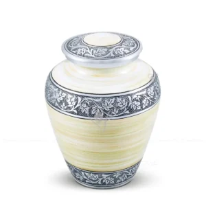 Morning Mist 9-inch Elite shaped aluminum cremation urn featuring a spray-painted white and light yellow finish with silver hand-chiselled floral engravings.