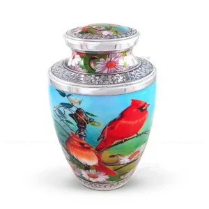 Cardinal Grace 10-inch Treisty shaped aluminum cremation urn featuring a high-gloss scenic graphic wrap with red cardinals and hand-engraved silver-tone floral bands.