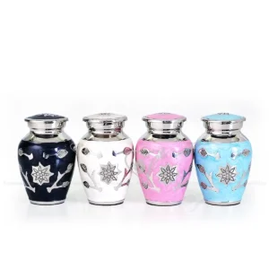 Florena Collection set of 4 brass keepsake urns in black, white, pink, and blue with hand-engraved floral motifs.